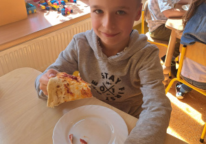 Dzieci konsumują wykonaną pizzę.