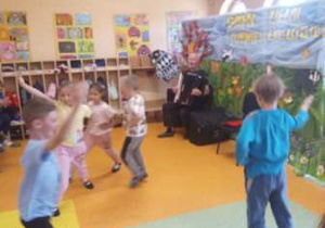 Dzieci uczestniczą w koncercie muzycznym, wykonują taniec.