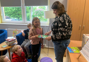 Dzieci wręczają podziękowanie pani z biblioteki.