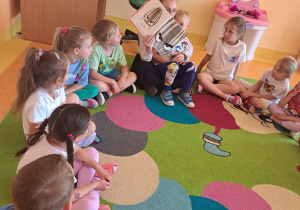 Dzieci słuchają bajki czytanej przez rodzica.