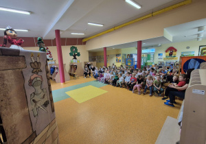 Dzieci oglądają teatrzyk w wykonaniu aktorów.
