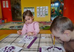 Dzieci wyklejają szablon śliwki wydzierankami.
