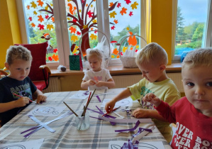 Dzieci wyklejają szablon śliwki wydzierankami.