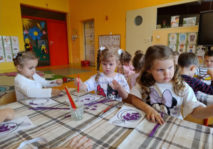 Dzieci wyklejają szablon śliwki wydzierankami.