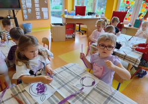 Dzieci wyklejają szablon śliwki wydzierankami.