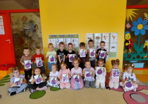 Grupa dzieci prezentuje prace plastyczną.