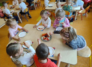 Dzieci wybierają kawałki różnych owoców oraz warzyw i nakładają je na talerze.