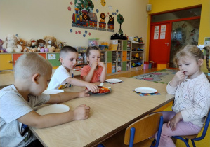 Dzieci wybierają kawałki różnych owoców oraz warzyw i nakładają je na talerze.