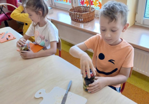Dzieci wkładają owoce do słoików.
