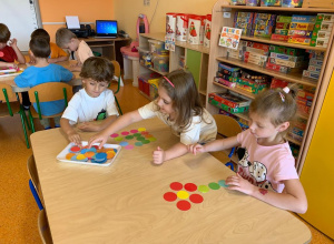 Dzieci układają obrazek z kolorowych kropek na stoliku.