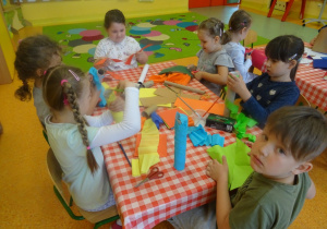 Sześcioro dzieci owija rolki kolorowymi wycinankami