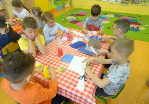 Sześcioro dzieci owija pudełka kolorowymi wycinankami