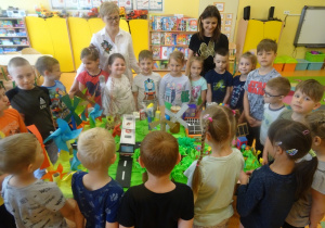 Dzieci wraz z panią Arletą i panią Eweliną stoją wokół stolika z makietą na temat "Moje ekologiczne miasto"