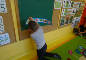 Chłopiec przypina do tablicy jeden z elementów piramidy zdrowia