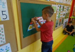 Chłopiec przypina do tablicy jeden z elementów piramidy zdrowia