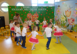 Dzieci z panią Dorotą tańczą w kole , trzymają się za ręce
