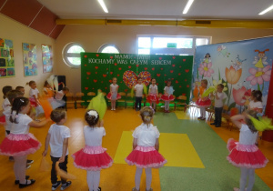 Dzieci ustawieni w kole trzymają chusteczki i tańczą