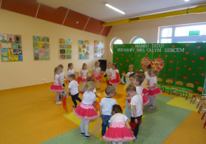 Dzieci ustawieni w kole trzymają chusteczki i tańczą