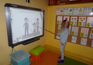 Natalka stoi przed tablicą i ocenia zachowanie przedstawiające na ilustracji