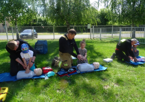 Troje dzieci pokazuje jak udzielić pierwszej pomocy
