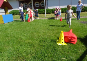 Dzieci ustawione w dwa rzędy, Liwka biegnie do pachołka przy którym stoi czerwony worek
