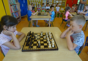 Hania i Krzysiu grają w szachy, siedzą na przeciwko siebie
