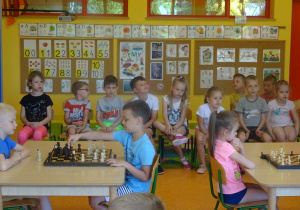 Franek i Kacper grają w szachy, dzieci siedzą na krzesłach na dywanie