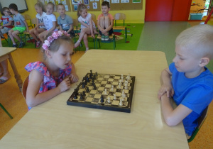Natalka i Franek siedzą na przeciwko siebie i grają w szachy