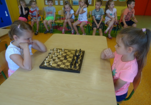 Marysia i Kaja siedzą na przeciwko siebie i grają w szachy
