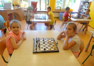 Przy trzech stolikach siedzą dzieci i grają w szachy