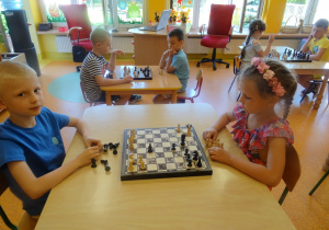 Przy trzech stolikach siedzą dzieci i grają w szachy