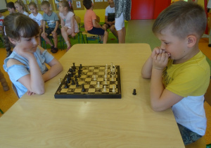 Amelka i Kuba siedzą na przeciwko siebie i grają w szachy