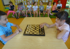 Kacper i Hania siedzą na przeciwko siebie i grają w szachy