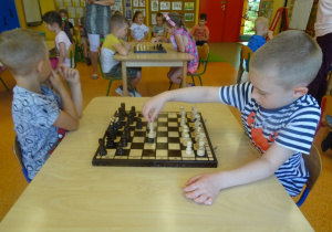 Krzysiu i Gabryś siedzą na przeciwko siebie i grają w szachy