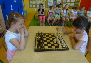 Marysia i Hania siedzą na przeciwko siebie i grają w szachy