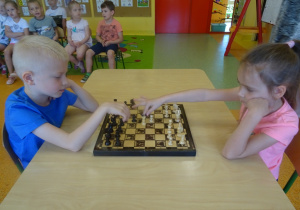 Franek i Kaja siedzą na przeciwko siebie i grają w szachy