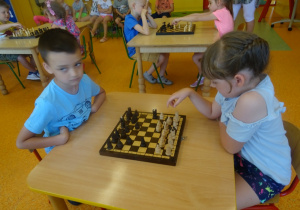 Kacper i Amelka siedzą na przeciwko siebie i grają w szachy