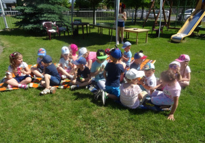Dzieci siedzą na kocach i jedzą lody