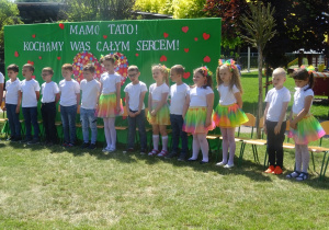 Dzieci stoją na tle zielonej tablicy , mówią wiersz