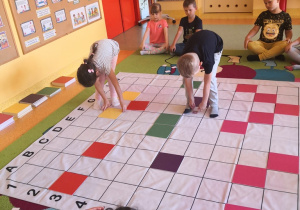 Dzieci układają kolorowe tabliczki wg kodu na macie