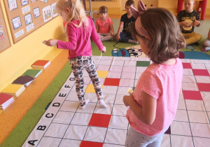 Dziewczynki układają kolorowe tabliczki wg kodu na macie