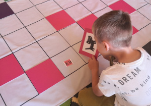 Chłopiec układa kolorowe tabliczki wg kodu na macie