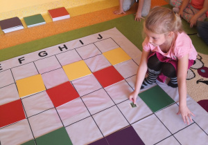 Dziewczynka układa kolorowe tabliczki wg kodu na macie