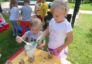 Dzieci przelewają piasek z wodą przez sitko