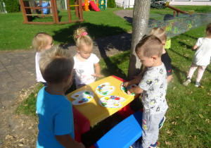 Dzieci maczają paluszki w farbie.