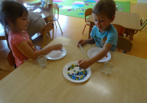 Dzieci układają na talerzu kolorowe cukierki