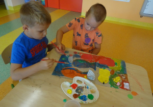 Chłopcy wykonują pracę plastyczną dowolną techniką, malują farbami.