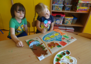 Dwójka dzieci wykonuje pracę plastyczną dowolną techniką, malują farbami.