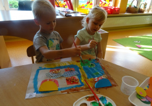 Dwójka dzieci wykonuje pracę plastyczną dowolną techniką, malują farbami.