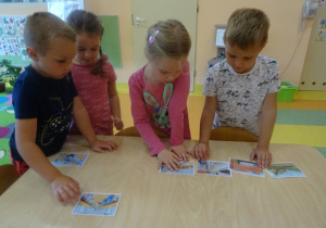 Czwórka dzieci układa wspólnie historyjkę obrazkową.